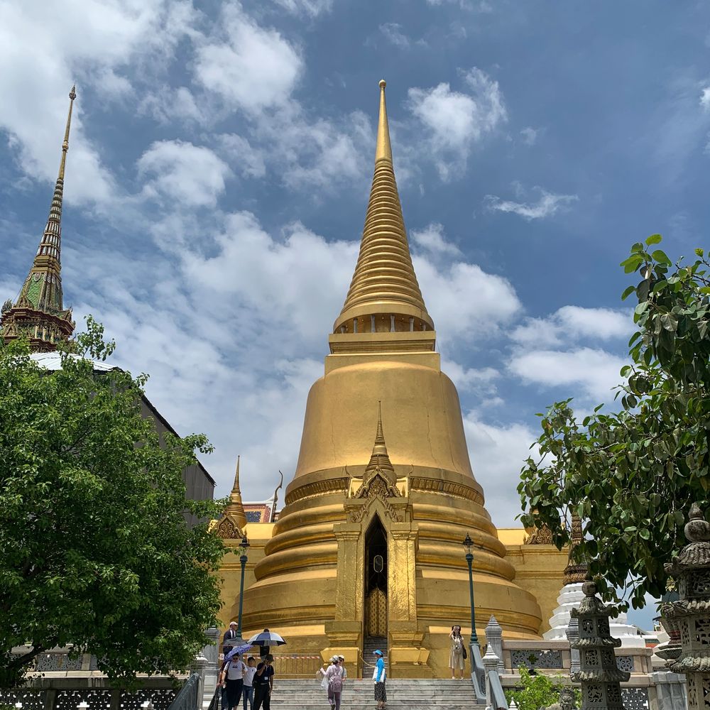 Golden chedi of Wat Phra Kaew rising against a cloudy sky in Bangkok