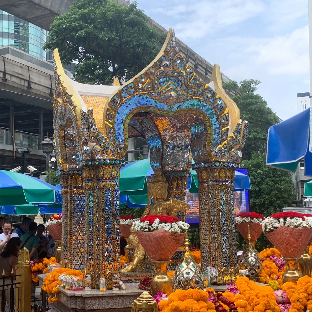 Colourful jewelled Erawan shrine decorated with marigold garlands at a city street corner