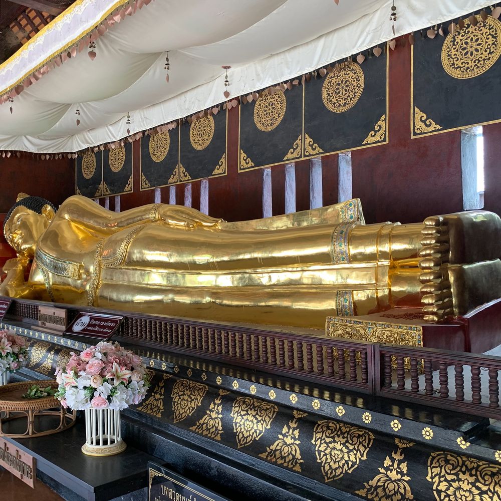 Golden reclining Buddha statue inside an ornate temple hall