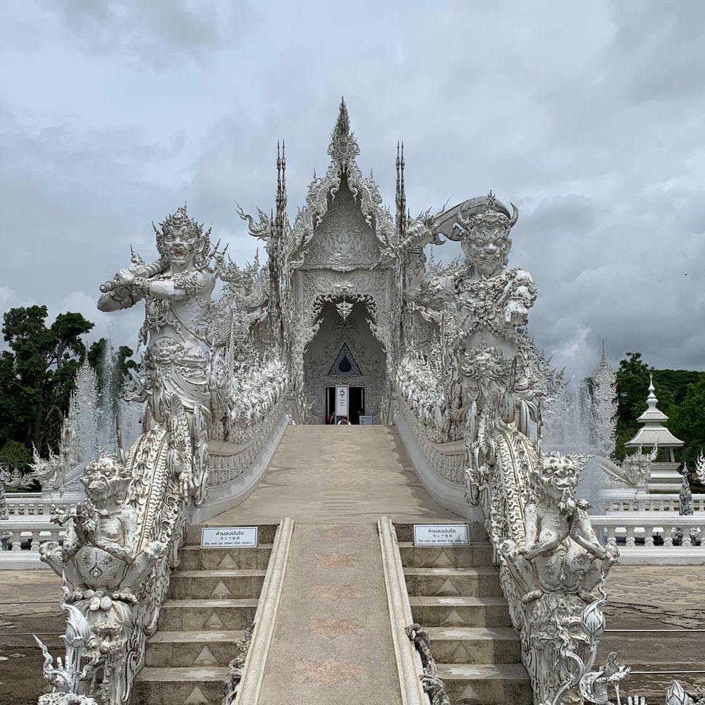 The silver-white Wat Rong Khun temple with its detailed sculpted entrance in Chiang Rai