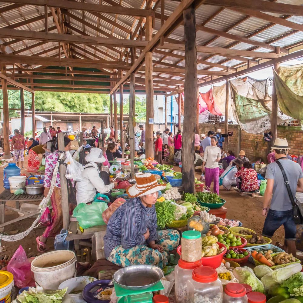 Busy covered local market with vendors selling fresh produce