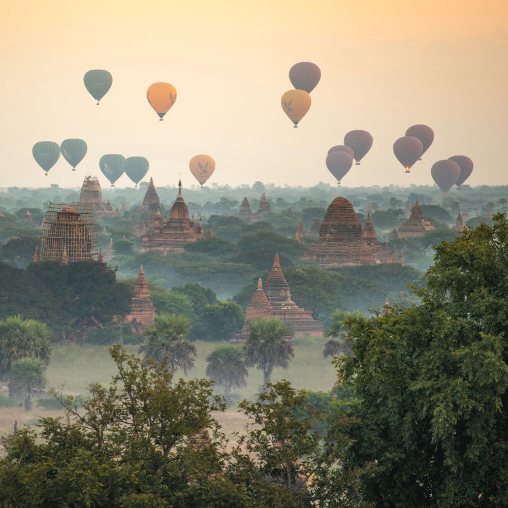 Hot-air balloons drifting over the misty temple plains of Bagan at dawn