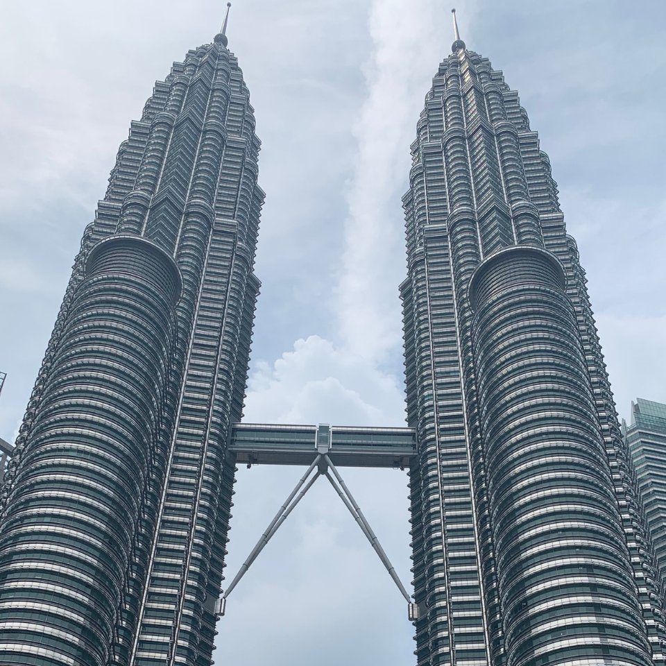 The Petronas Twin Towers connected by their skybridge against a cloudy sky in Kuala Lumpur