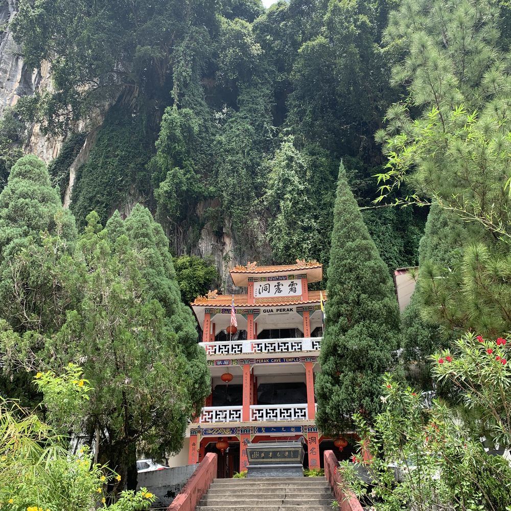 Ornate red Chinese cave temple set against limestone cliffs and greenery near Ipoh
