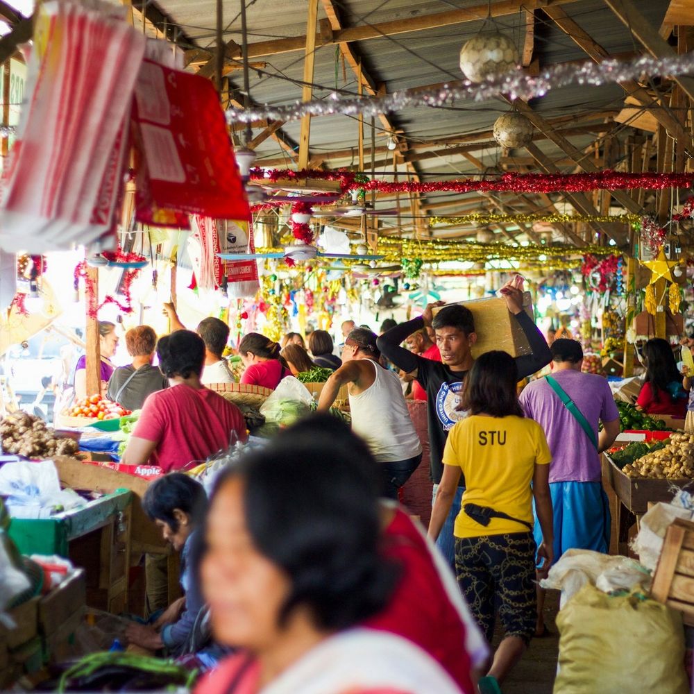 Bustling local covered market in the Philippines with fresh produce and festive decorations