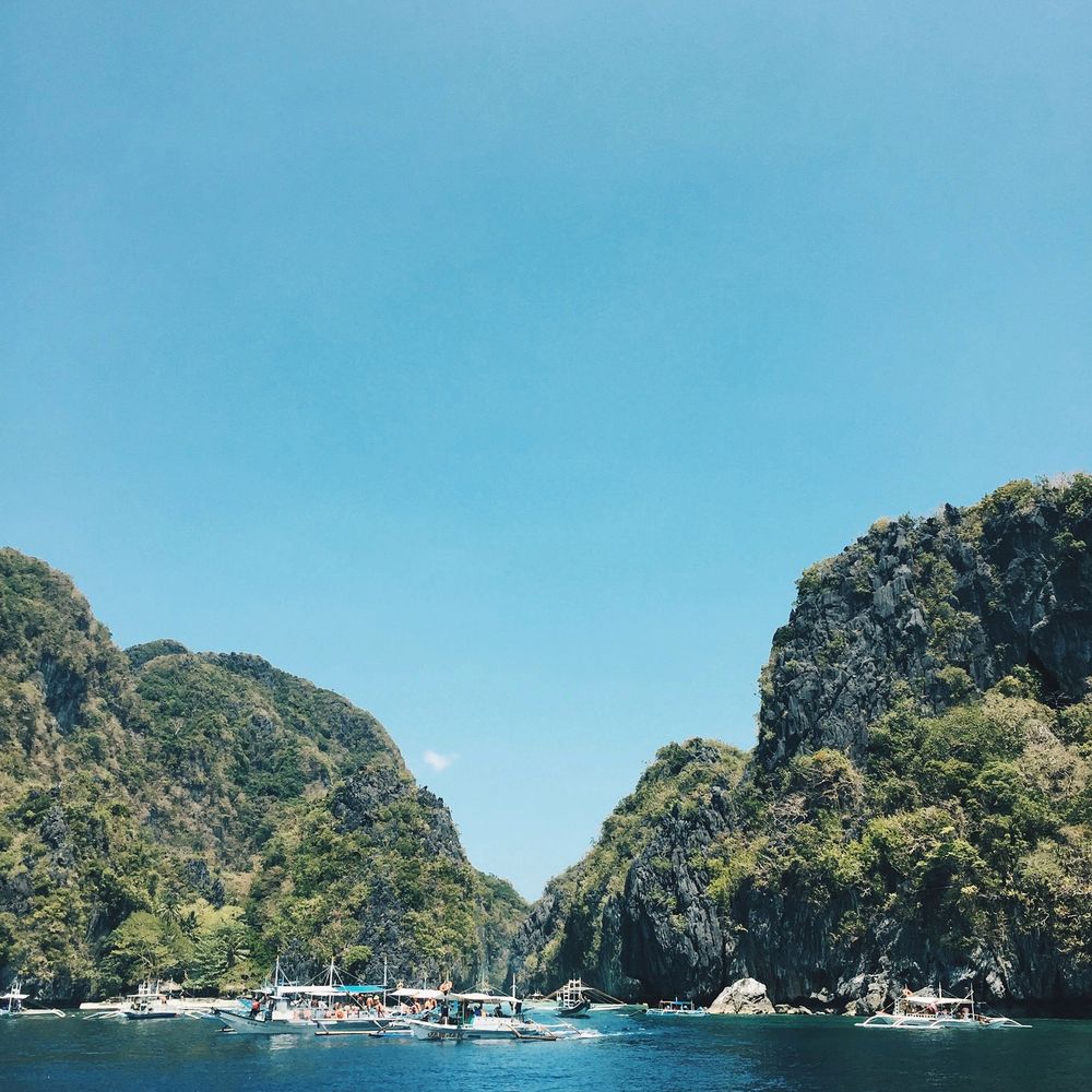 Filipino outrigger boats among steep limestone cliffs in the sea near El Nido
