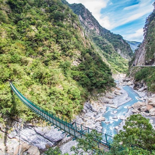 Suspension bridge over a river gorge amid the green cliffs of Taroko National Park
