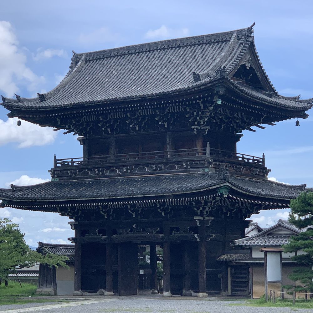 Massive wooden temple gate beneath a blue sky in Kyoto