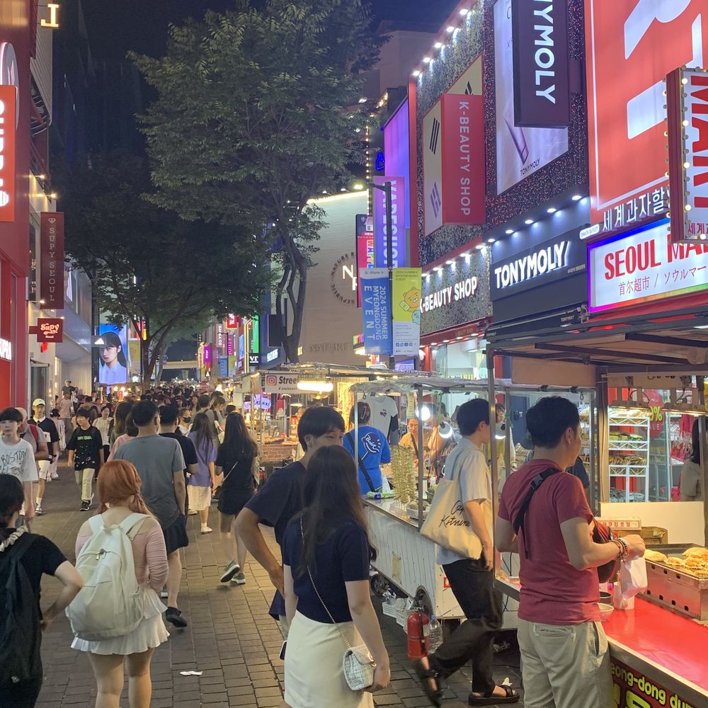 Crowds and neon storefronts along the lively Myeongdong shopping street at night